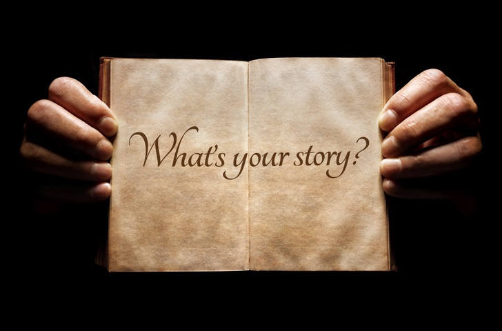 A pair of hands holding open a book with "what's your story" written inside
