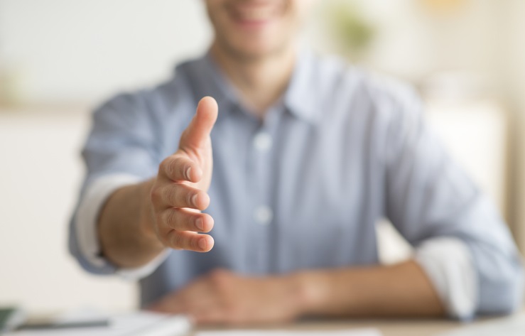 A smiling man with his hand outstretched for a handshake