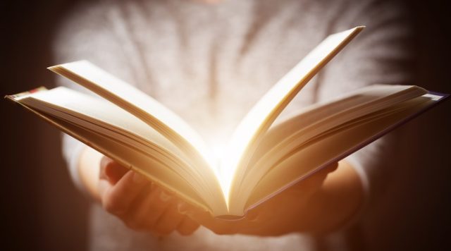 Light coming from book in woman's hands in gesture of giving