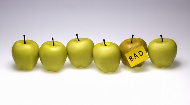 6 green apples in a line; 1 has a sticky note on it that says "bad"