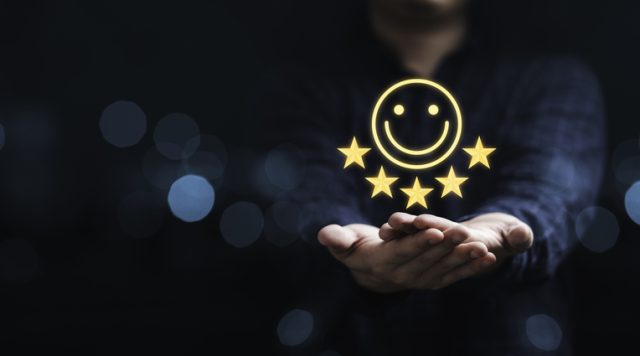 A person holding out their hands in front of them as if presenting something. Hovering over their hands is a smiley face with 5 stars under it