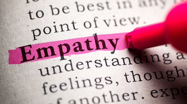 A dictionary page with the word "empathy" and its definition. The word "empathy" is being highlighted with a pink marker.