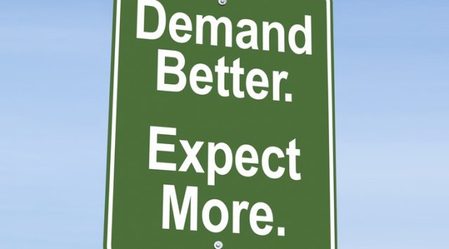 A green sign with white letters that says "Demand Better. Expect More."