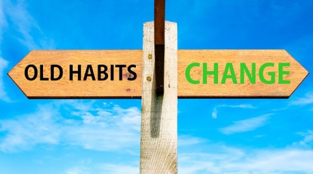 A sign with an arrow pointing to the left that says "old habits" and an arrow pointing to the right that says "change"