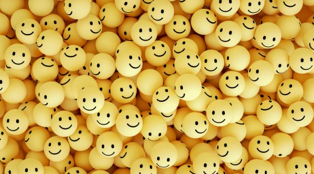 A bunch of yellow ping pong balls with smiley faces on them