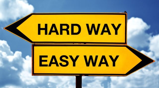 Two signs pointing in opposite directions. One says "hard way", the other says "easy way"