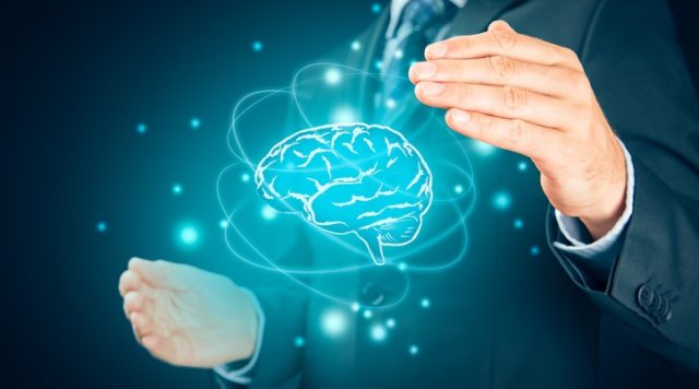 The image shows a man in a suit holding his hands around a glowing, holographic brain. The brain is stylized in blue, surrounded by orbital-like lines and floating particles, giving it a futuristic or digital appearance.