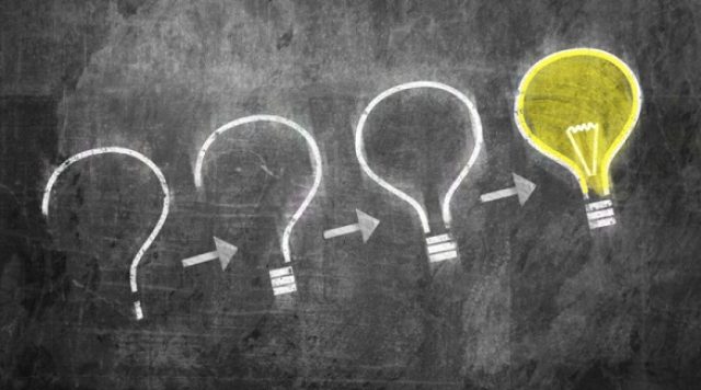 A chalkboard with the drawing of a question mark progressing into a light bulb.