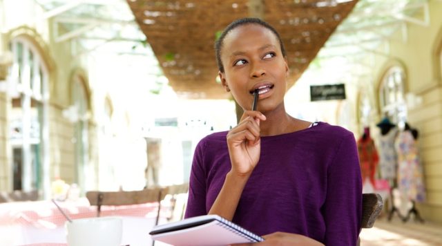 Young african woman at cafe writing notes
