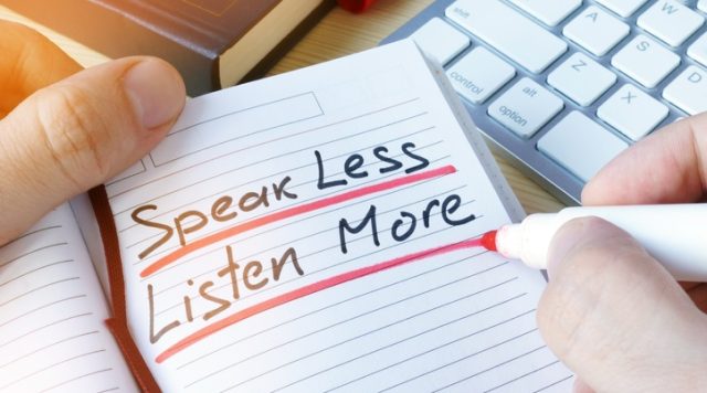 A notebook in which "speak less, listen more" is written in black ink and underlined in red ink