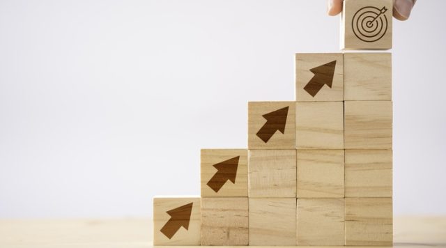 Building blocks ascending up, diagonally to the right, towards a bullseye