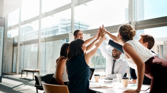 A group of people in an office high-fiving