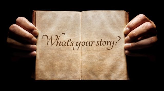 A pair of hands holding open a book with "what's your story" written inside